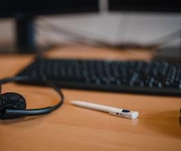 Nahaufnahme vom Arbeitsplatz mit Tastatur, Maus und Headset.