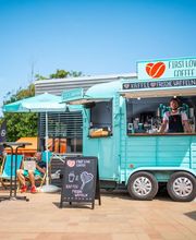 FirstLoveCoffee GmbH - Kaffee Catering Berlin - Mobiler Kaffeeanhänger mit Barista, Bio-Kaffee, frischen Waffeln und Sitzbereich bei sonnigem Outdoor-Event, passend für Sommerfest und Event Catering.