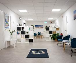 Foyer mit Sitzgelegenheiten, weißen Regalen und einem Fußläufer mit WBS TRAINING Logo.