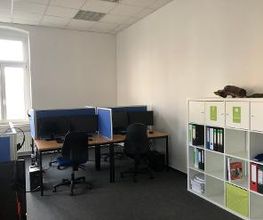 Schulungsraum mit 2 Arbeitsplätzen jeweils mit 2 Bildschirmen, einem Bürostuhl, Tastatur, Maus und Headset. Dahinter ein Bücherregal.