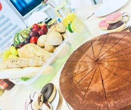 Ein gedeckter Tisch mit Kuchen, Donuts, Baguette und Obst.