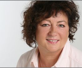 Eine Frau mit mittellangen brünetten Haaren und heller Bluse.