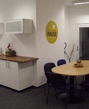 Ein Pausenraum mit einer Küche, einem ovalen Tisch und mehreren Stühlen