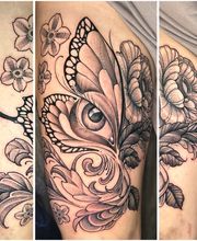 Detailreiches Black-and-Grey-Tattoo mit Schmetterling, Auge, Blüten, Blättern und ornamentalen Linien im femininen Fineline-Stil.