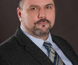 Portrait vom Bildungsreferent Manuel Normann. Ein Mann mit dunklen Haaren und Bart, der einen Anzug und Krawatte trägt.