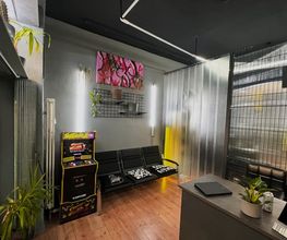 Warteraum mit schwarzen Sitzbänken farbigem Arcade Automat Pflanzen grauen Wänden und Kunstwerken im modernen Stil.