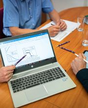 Besprechung am Tisch mit Laptop, Tablet und Notizen