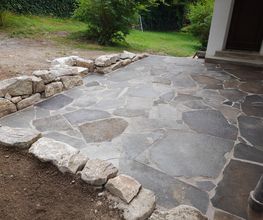 Terrasse mit Porphyrplatten und Sandsteinmauer