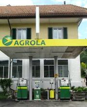 AGROLA Tankstelle in Walkringen, zwei Tanksäulen und ein Zahlterminal überdacht, im Hintergrund Wohnhaus mit mehreren Fenstern, frontale Aufnahme