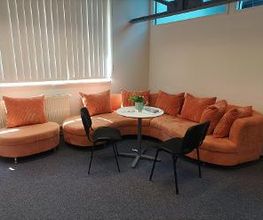 Gemütliche Sitzecke mit einem orangefarbenen Sofa und Tischgruppe.