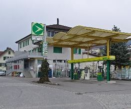 AGROLA Tankstelle in Kaltbrunn; geschwungen Überdachung. Zwei Tanksäulen. In Kurve gelegen. Rechts Erdsäcke.