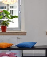 Gemütliche Sitzbank mit Kissen am Fenster. Schöne Zimmerpflanzen im Hintergrund.