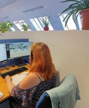 Teilnehmerin sitzt am Arbeitsplatz mit Headset und lernt virtuell