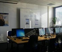 Mehrere PC-Arbeitsplätze mit Monitoren, Tastatur, Maus und Headset.
