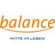 Das Logo zeigt den Schriftzug „balance“ in einer geschwungenen, orangefarbenen Schrift. Unter dem Wort verläuft eine sanfte, ebenfalls orangefarbene Linie, die wie ein Bogen oder eine Balance-Linie wirkt. Darunter steht in blauer Großschrift der Slogan „MITTE IM LEBEN“. Das Design vermittelt Harmonie, Stabilität und Ausgeglichenheit.