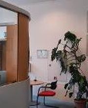 Empfangsbereich des Standortes mit Tresen, Tisch und Pflanzen.