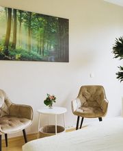 Heller Behandlungsraum von Physiotherapie Birkhoff mit Therapieliege, Sitzbereich und ruhigem Waldmotiv. Das Bild vermittelt eine angenehme Atmosphäre für individuelle Physiotherapie Magdeburg, Schmerztherapie Magdeburg und ganzheitliche Behandlung.