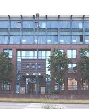 Außenansicht vom Gebäude, welches eine rot-braune Klinkerfassade und viele Fenster hat.