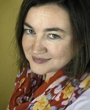 Portrait einer Bildungsreferentin, die ein geblühmtes Tuch um den Hals trägt und freundlich in die Kamera schaut.