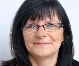 Portrait einer Bildungsreferentin mit schwarzen Haaren und Brille. Die Dame lächelt freundlich in die Kamera.