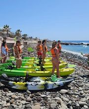instructor experto dando las instrucciones en la arena a personas con kayaks a su lado