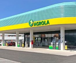 AGROLA Tankstelle in Murten, überdacht, mit TopShop, mehrere Tanksäulen, geschwungenes Dach (gelb/türkis) mit AGROLA Logo
