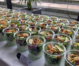 dean&david Catering | Pforzheim - Chicken Teriyaki Bowls im Glas mit Reis, Salat, Gurke, Limette und Frühlingszwiebeln auf einem hellen Buffet für Firmenveranstaltungen.