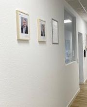 Langer Flurbereich mit Flyerständer und Bildern an der Wand.
