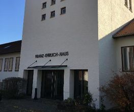 Eingang zum Franz-Ehrlich-Haus mit Überdachung und Büschen links und rechts.