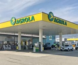 AGROLA Tankstelle in Grenchen; überdacht mit TopShop. Grosses Dach mit zwei AGROLA Schriftzügen; im Hintergrund Landi Laden