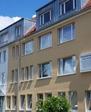 Gelbes Gebäude mit Fenstern und Eingang mit Überdachung.