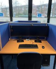 Ein Arbeitsplatz mit Fenstersicht. Auf dem Tisch stehen zwei Monitore, eine Tastatur und eine Maus. Unter dem Tisch befindet sich ein Computer.