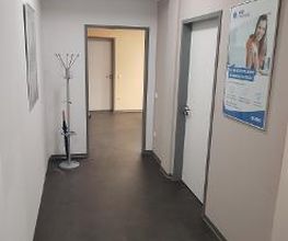 Bild vom Flur im Innenbereich. Zu sehen ist ein Garderobenständer, mehre Türen zu Räumen sowie ein Werbeplakat an der Wand.