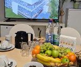 Gedeckter Tisch mit Kaffee, Obst und Plätzchen. Dahinter ein Bildschirm auf dem die digitale Lernumgebung zu sehen ist.