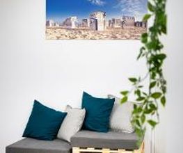 Sitzgelegenheit aus Europaletten mit Kissen. An der Wand hängt ein Bild von Strandkörben. Im Vordergrund hängt Efeu.