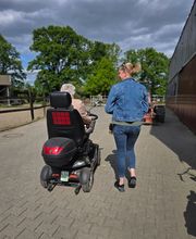 Gemeinsam unterwegs und weiterhin am Alltag teilnehmen: Eine Seniorin ist mit ihrem Elektromobil unterwegs und wird von einer Begleitperson unterstützt. Ein Beispiel dafür, wie persönliche Betreuung Mobilität und Lebensqualität fördern kann.