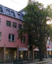 Außenansicht vom Gebäude an einer Straße. Rote Fassade und WBS TRAINING Schild. 