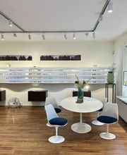 Moderner Verkaufsraum von Newels Eyewear in Münster mit einer großen Auswahl an Brillenfassungen. Die übersichtliche Präsentation und der Beratungsbereich bieten ein hochwertiges Umfeld für die Auswahl einer neuen Brille.