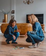 Webstudio Dresden Dynamische Gesprächssituation zwischen zwei Frauen, kreative Zusammenarbeit mit visuellen Materialien am Boden.