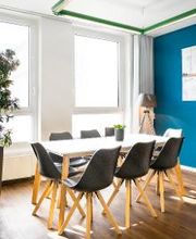 Ein weißer Tisch mit schwarzen, modernen Stühlen im Aufenthaltsraum.