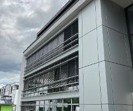 Außenansicht des Gebäudes. Graue Fassade und Fensterfront.