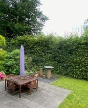 Garten mit Gartentisch und Stühlen.