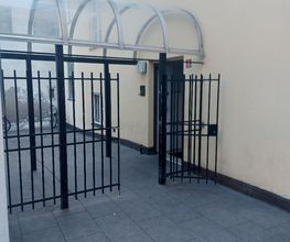 Schwarzes Gittertor zum Eingang mit Überdachung.