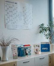 Regal mit Flyern und Büchern. Darüber ein Jahres-Wandkalender.