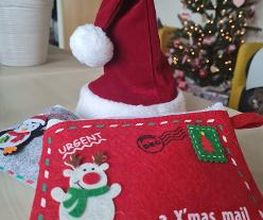 Eine Rote Nikolausmütze und ein roter Stoffumschlag mit der Aufschrift "Urgent - A X'mas mail"