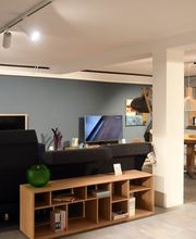 Moderner Wohnbereich mit elegantem Sofa, Holz-Media-Möbeln und stilvoller Wandgestaltung bei Möbel Schmitz in Trier. Ihr Experte für ganzheitliches Interior Design und Markenmöbel.