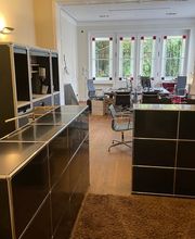 Weitläufiger Blick durch die Büroräume der PAKT Gruppe mit mehreren Arbeitsplätzen und Besprechungsmöglichkeiten.