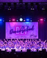 D.D.Project - Hip-Hop Tanzschule Dresden Große Tanzgruppe bei einer Bühnenaufführung mit farbiger Lichtshow und Publikum, ideal für Inhalte zu Tanzschule, Showdance und Bühnenperformance.