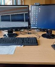 PC-Arbeitsplatz mit zwei Monitoren, Tastatur, Maus, Webcam und Headset.