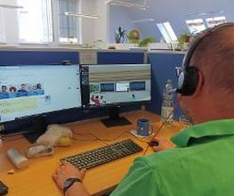 Teilnehmer sitzt am Arbeitsplatz und lernt in der virtuellen lernumgebung und hört mit Headset dem Unterricht zu